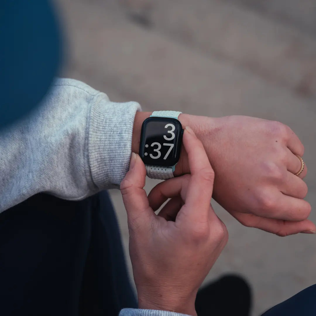 Person adjusting a smartwatch on their wrist with a blurred background